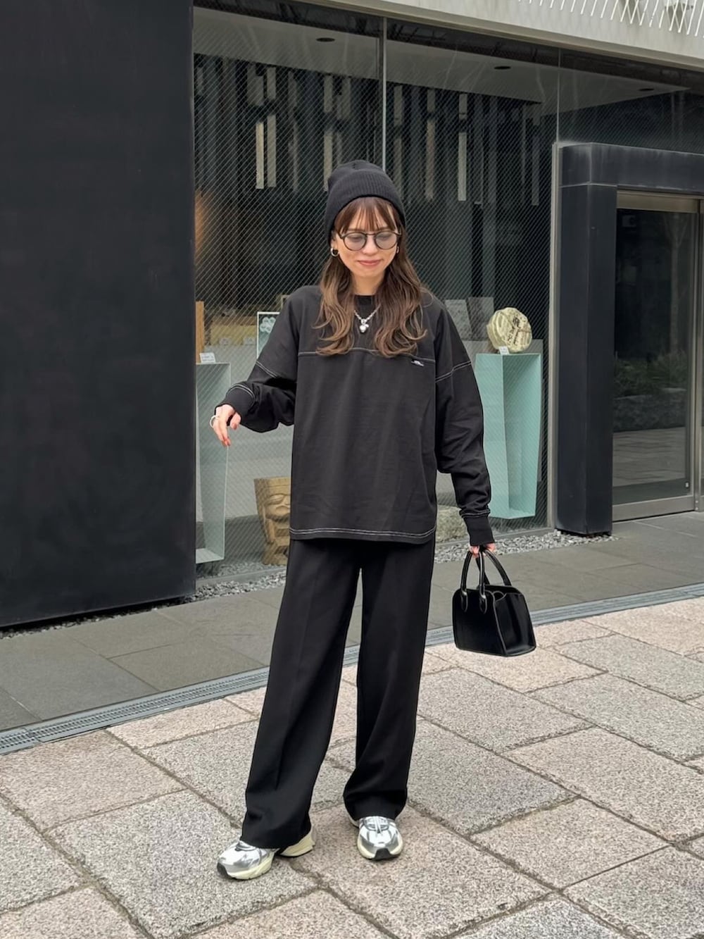 ブラック系のTシャツ/カットソー、ブラック系のスラックス、ホワイト系のスニーカーを着用したレディースの春コーディネートの5枚目の写真