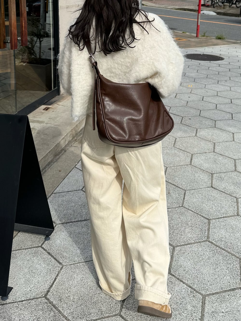 ホワイト系のニット/セーター、ホワイト系のデニムパンツ、ブラウン系のショルダーバッグを着用したレディースの冬コーディネートの3枚目の写真