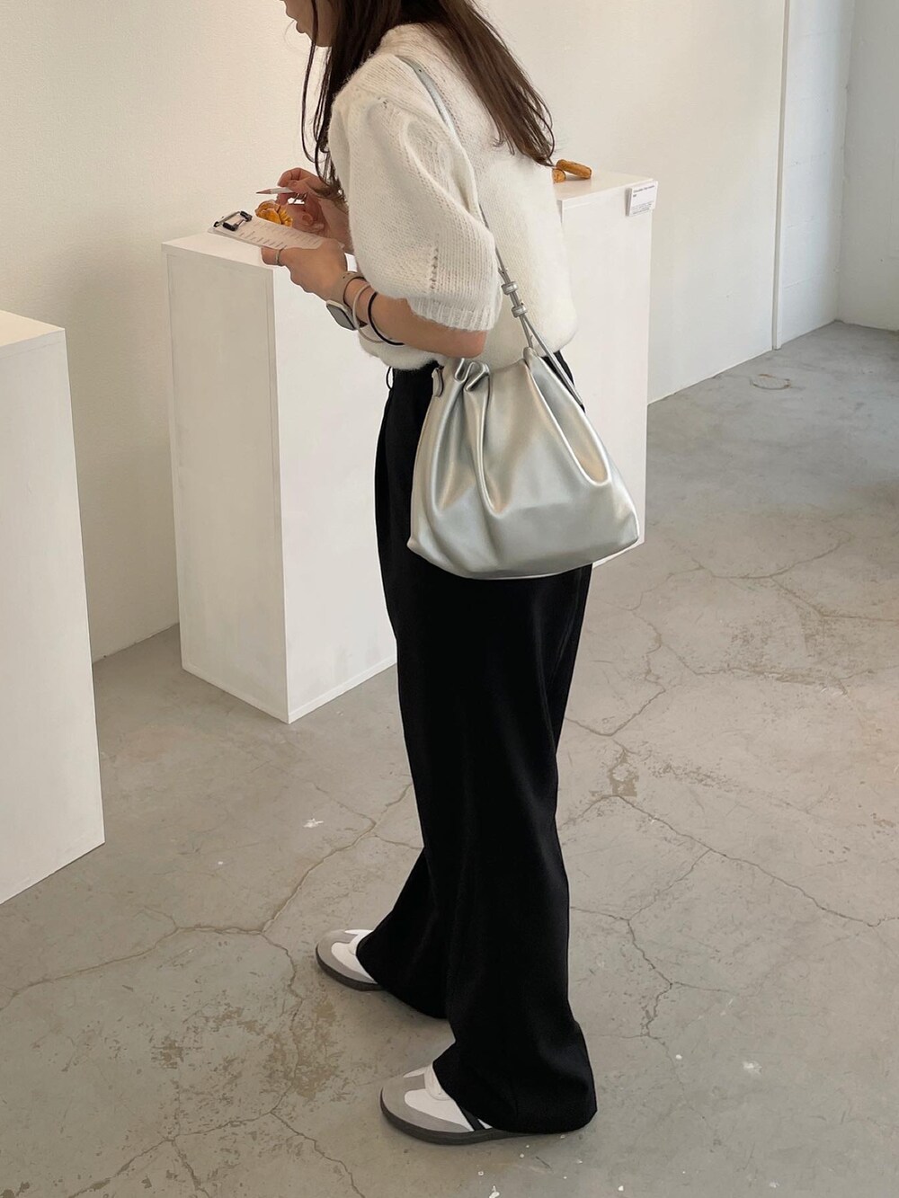 ホワイト系のニット/セーター、シルバー系のショルダーバッグ、ホワイト系のスニーカーを着用したレディースの秋コーディネートの5枚目の写真