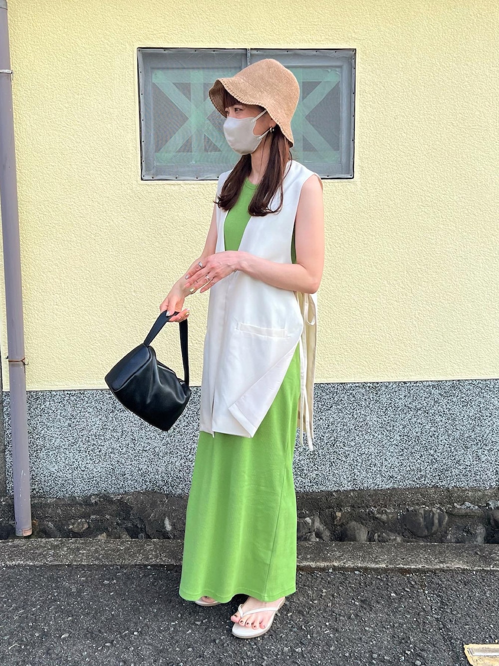 ホワイト系のベスト、グリーン系のワンピース、ベージュ系のハットを着用したレディースの夏コーディネートの2枚目の写真