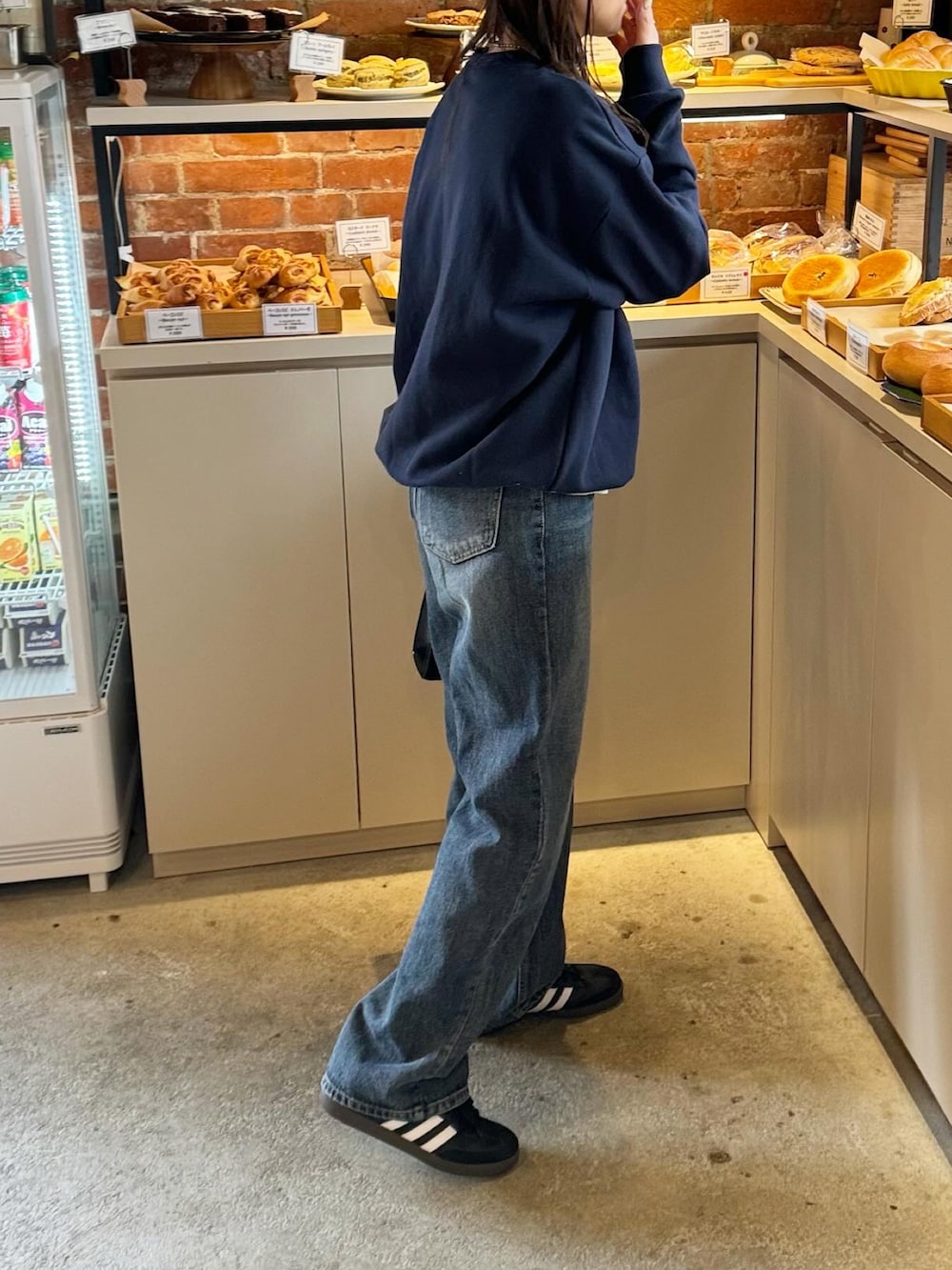 ブルー系のスウェット、ブラック系のスニーカー、ブラウン系のキャップを着用したレディースの冬コーディネートの3枚目の写真