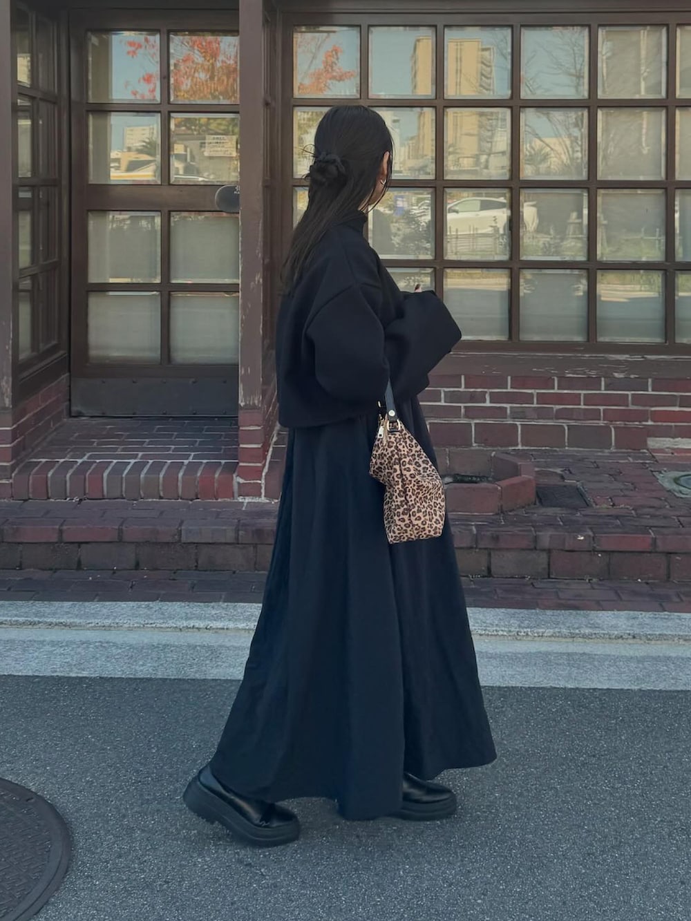 ブラック系のワンピース、ブラウン系のハンドバッグ、シルバー系のリングを着用したレディースの秋コーディネートの3枚目の写真