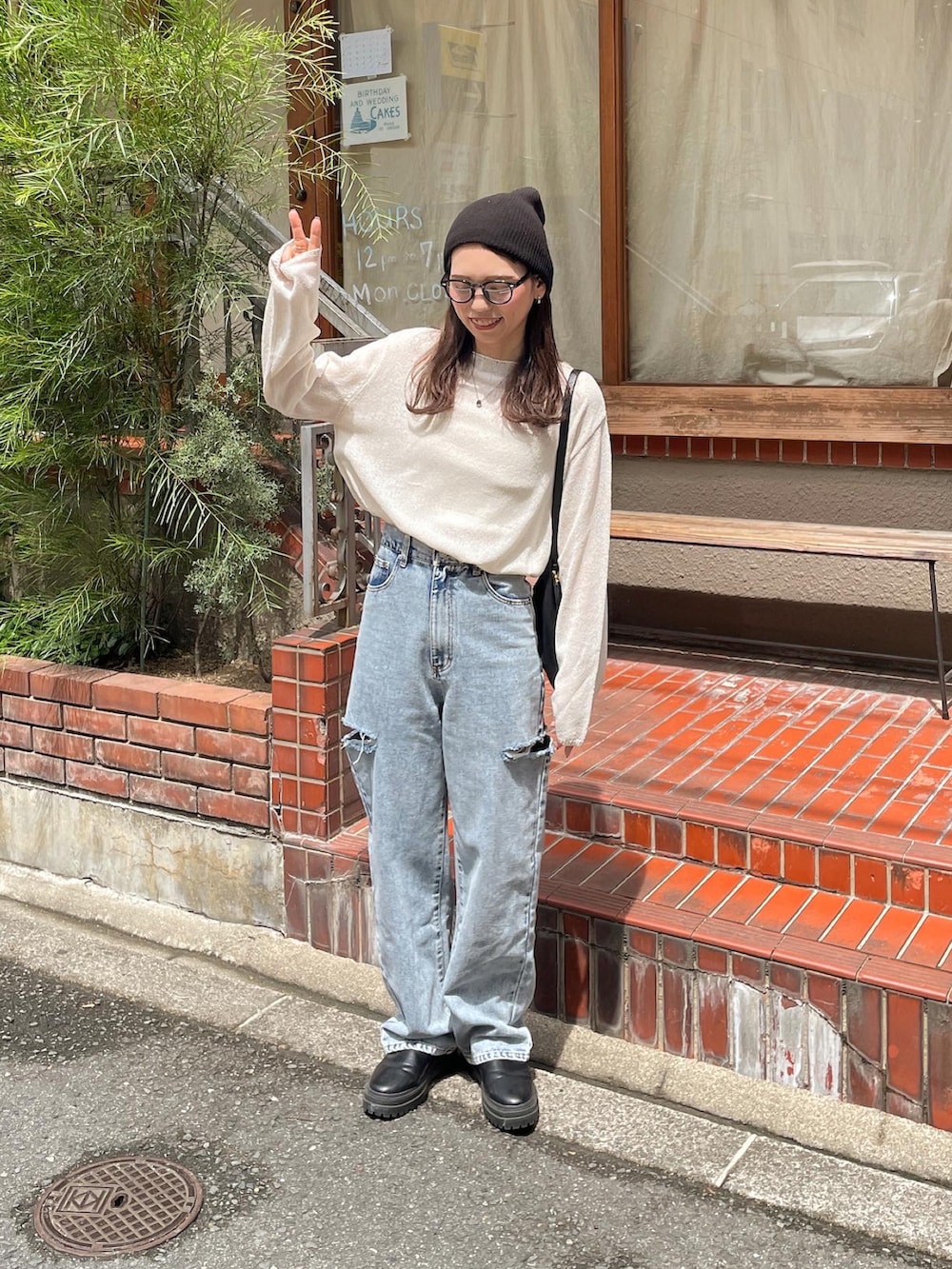 ホワイト系のニット/セーター、ブルー系のデニムパンツ、ブラック系のショルダーバッグを着用したレディースの夏コーディネートの3枚目の写真