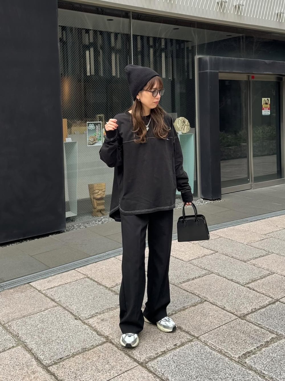 ブラック系のTシャツ/カットソー、ブラック系のスラックス、ホワイト系のスニーカーを着用したレディースの春コーディネートの3枚目の写真