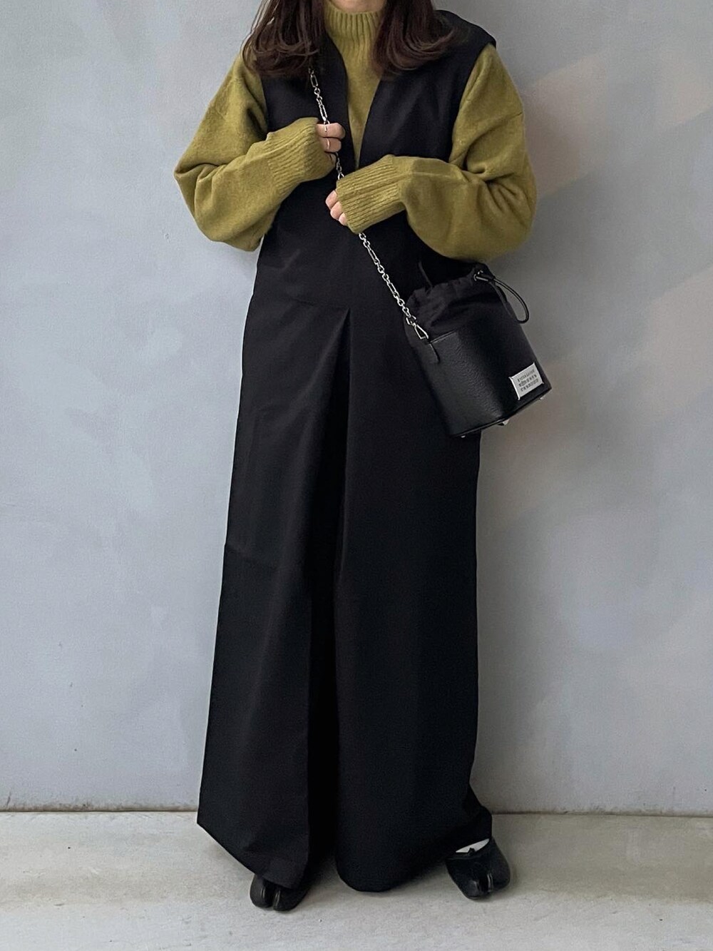 ブラック系のサロペット/オーバーオール、グリーン系のニット/セーターを着用したレディースの冬コーディネートの2枚目の写真