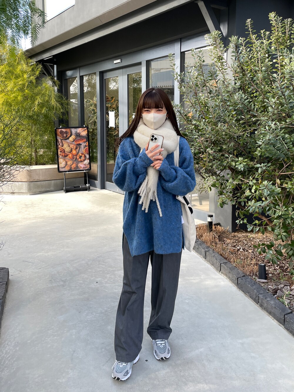 ブルー系のニット/セーター、ベージュ系のスニーカー、ホワイト系のマフラーを着用したレディースの冬コーディネートの2枚目の写真