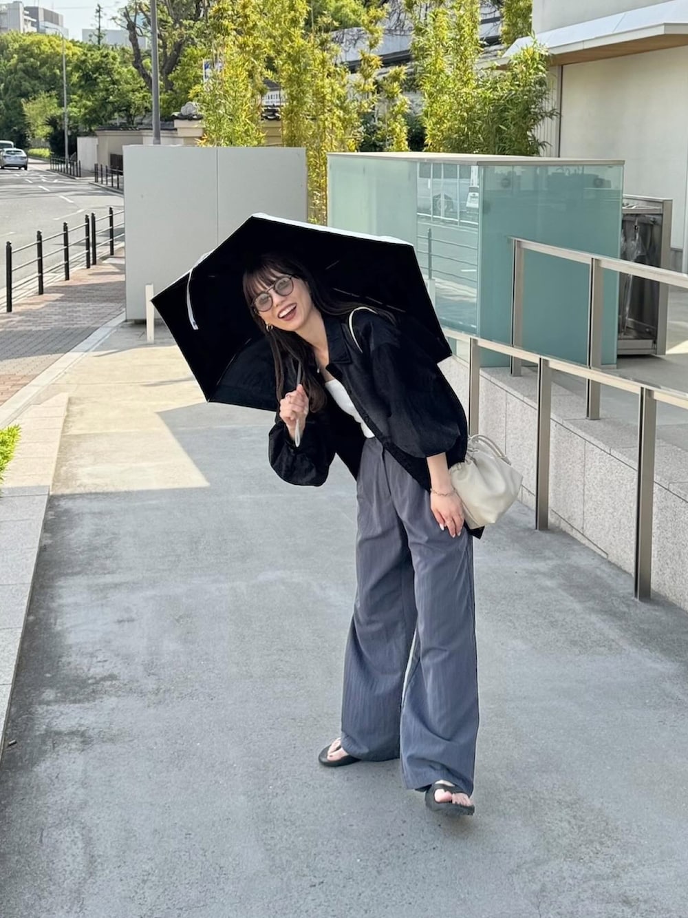 ホワイト系のショルダーバッグ、ベージュ系の折りたたみ傘を着用したレディースの春コーディネートの2枚目の写真