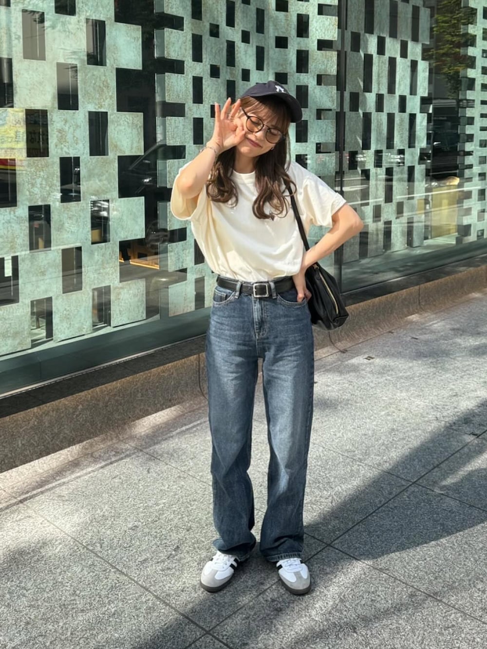 ホワイト系のTシャツ/カットソー、ブルー系のデニムパンツ、ブラック系のショルダーバッグを着用したレディースの春コーディネートの2枚目の写真