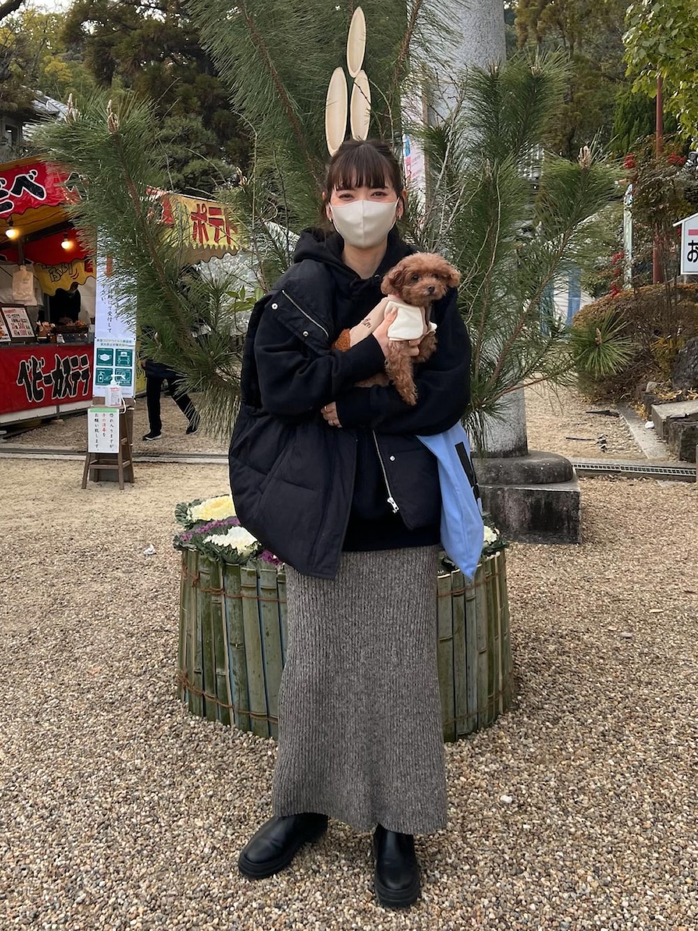 ブラック系のダウンベスト、グレー系のスカート、ブラック系のブーツを着用したレディースの冬コーディネートの2枚目の写真