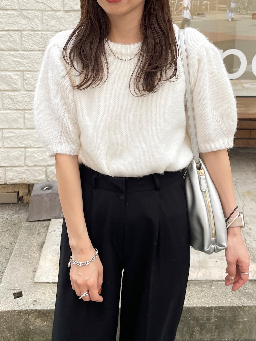 ホワイト系のニット/セーター、シルバー系のショルダーバッグ、ホワイト系のスニーカーを着用したレディースの秋コーディネートの3枚目の写真