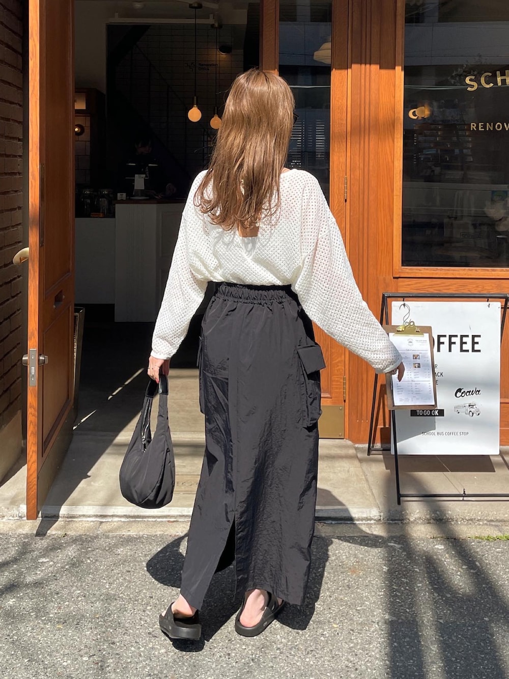 ホワイト系のニット/セーター、ブラック系のスカート、ブラック系のハンドバッグを着用したレディースの春コーディネートの4枚目の写真