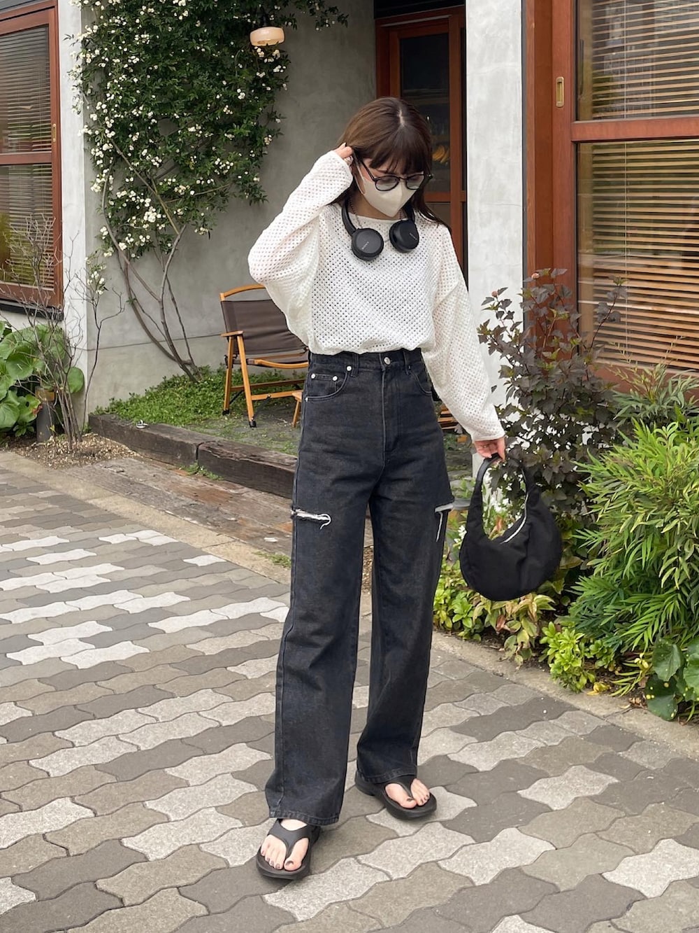 ホワイト系のニット/セーター、ブラック系のデニムパンツ、ブラック系のハンドバッグを着用したレディースの春コーディネートの2枚目の写真