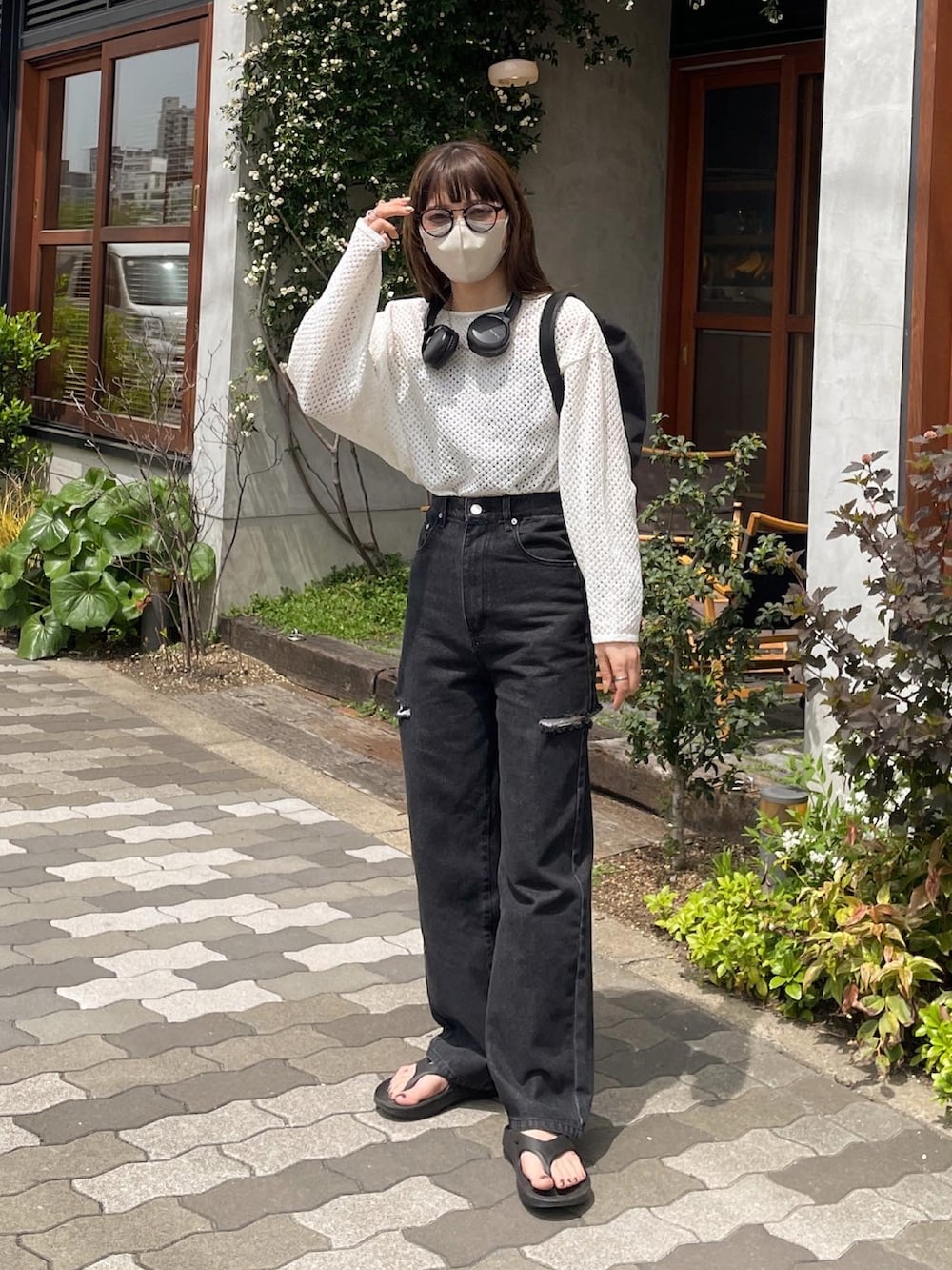 ホワイト系のニット/セーター、ブラック系のデニムパンツ、ブラック系のハンドバッグを着用したレディースの春コーディネートの5枚目の写真
