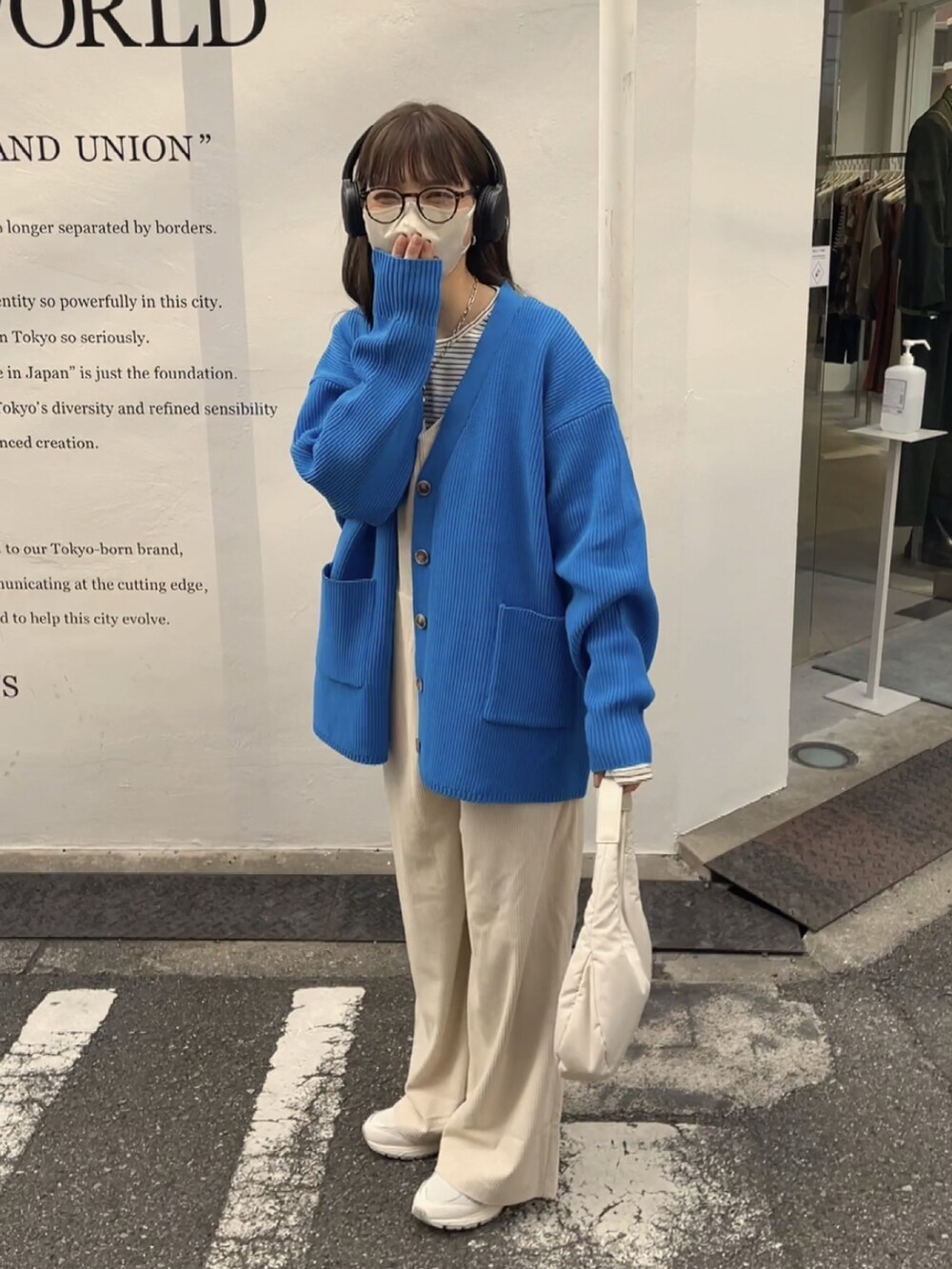 ブルー系のカーディガン/ボレロ、ホワイト系のサロペット/オーバーオール、ホワイト系のスニーカーを着用したレディースの冬コーディネートの2枚目の写真