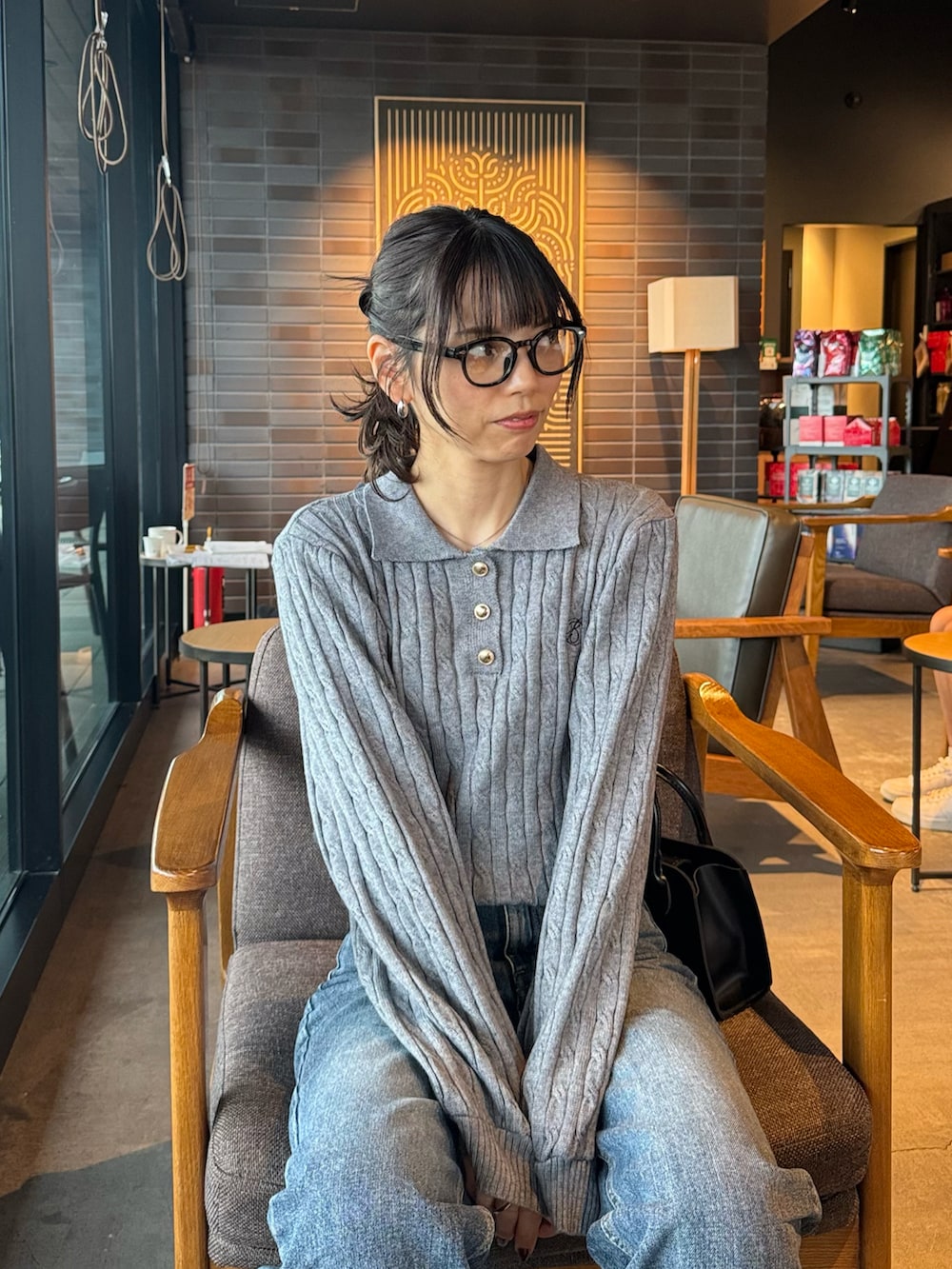 グレー系のニット/セーター、ブルー系のデニムパンツを着用したレディースの秋コーディネートの2枚目の写真