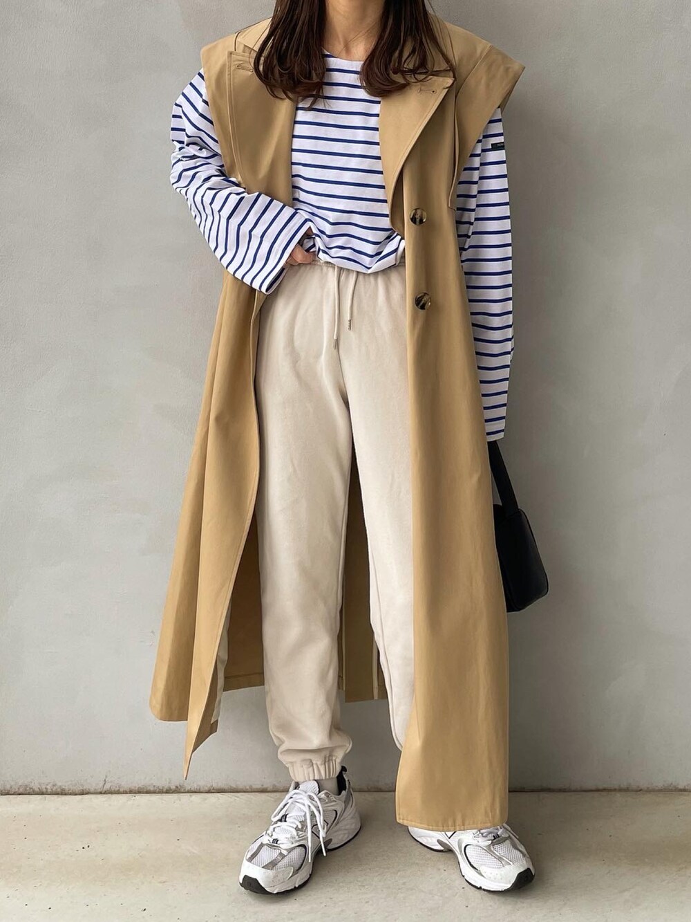 ベージュ系のトレンチコート、ホワイト系のTシャツ/カットソー、ホワイト系のスニーカーを着用したレディースの春コーディネートの2枚目の写真