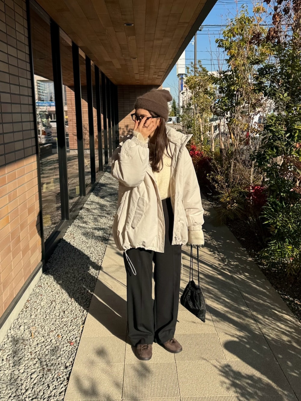 ホワイト系のダウンジャケット/コート、ホワイト系のニット/セーター、ブラック系のショルダーバッグを着用したレディースの冬コーディネートの3枚目の写真