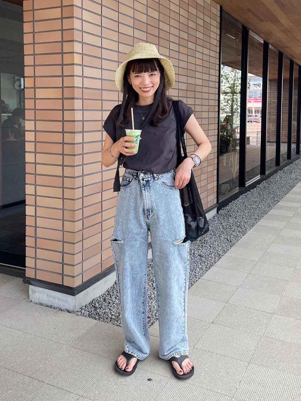 ブルー系のデニムパンツ、ブラック系のトートバッグ、ベージュ系のハットを着用したレディースの夏コーディネートの2枚目の写真