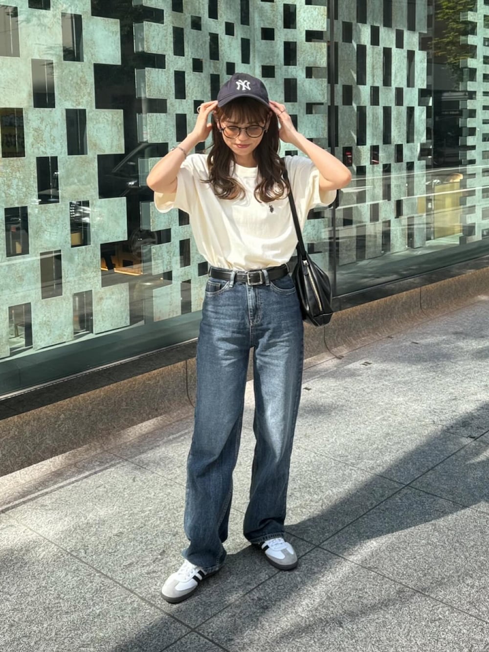 ホワイト系のTシャツ/カットソー、ブルー系のデニムパンツ、ブラック系のショルダーバッグを着用したレディースの春コーディネートの3枚目の写真