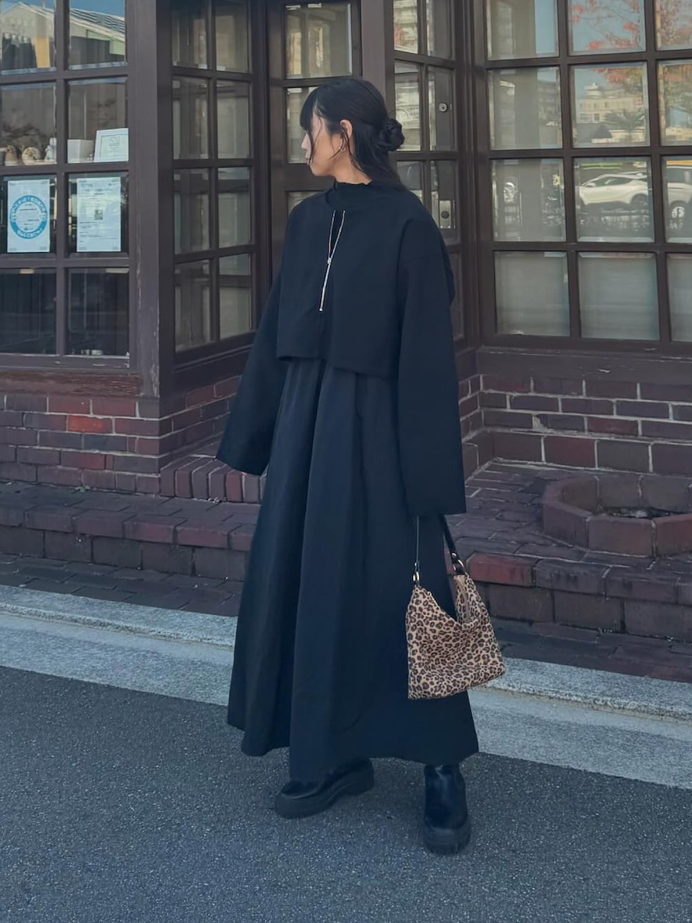 ブラック系のワンピース、ブラウン系のハンドバッグ、シルバー系のリングを着用したレディースの秋コーディネートの2枚目の写真