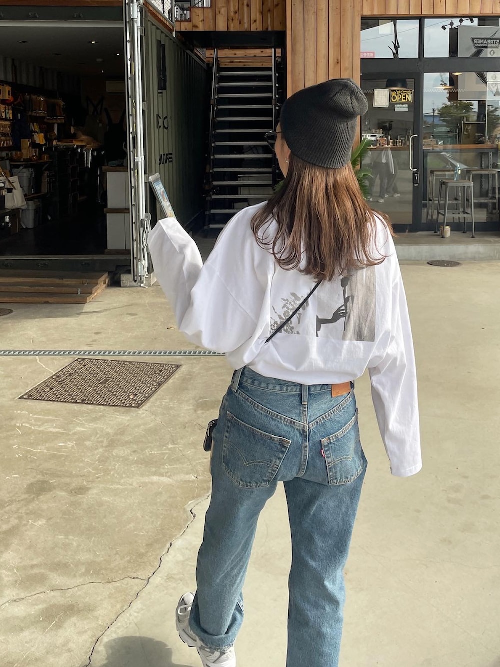 ホワイト系のTシャツ/カットソー、ブルー系のデニムパンツ、ホワイト系のスニーカーを着用したレディースの秋コーディネートの5枚目の写真