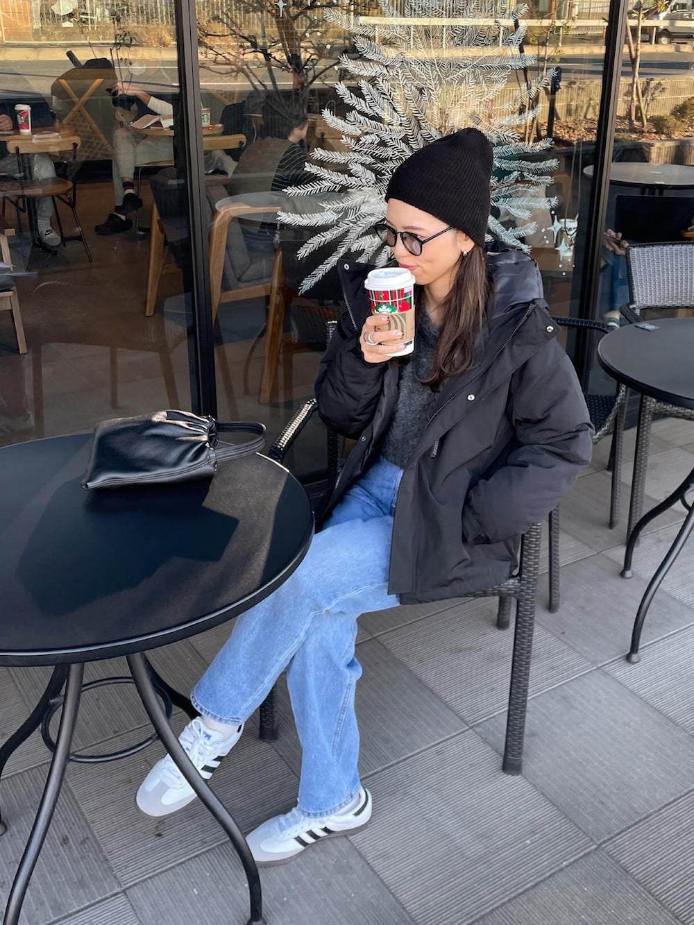 ブラック系のダウンジャケット/コート、ホワイト系のスニーカー、ブラック系のニットキャップ/ビーニーを着用したレディースの冬コーディネートの3枚目の写真