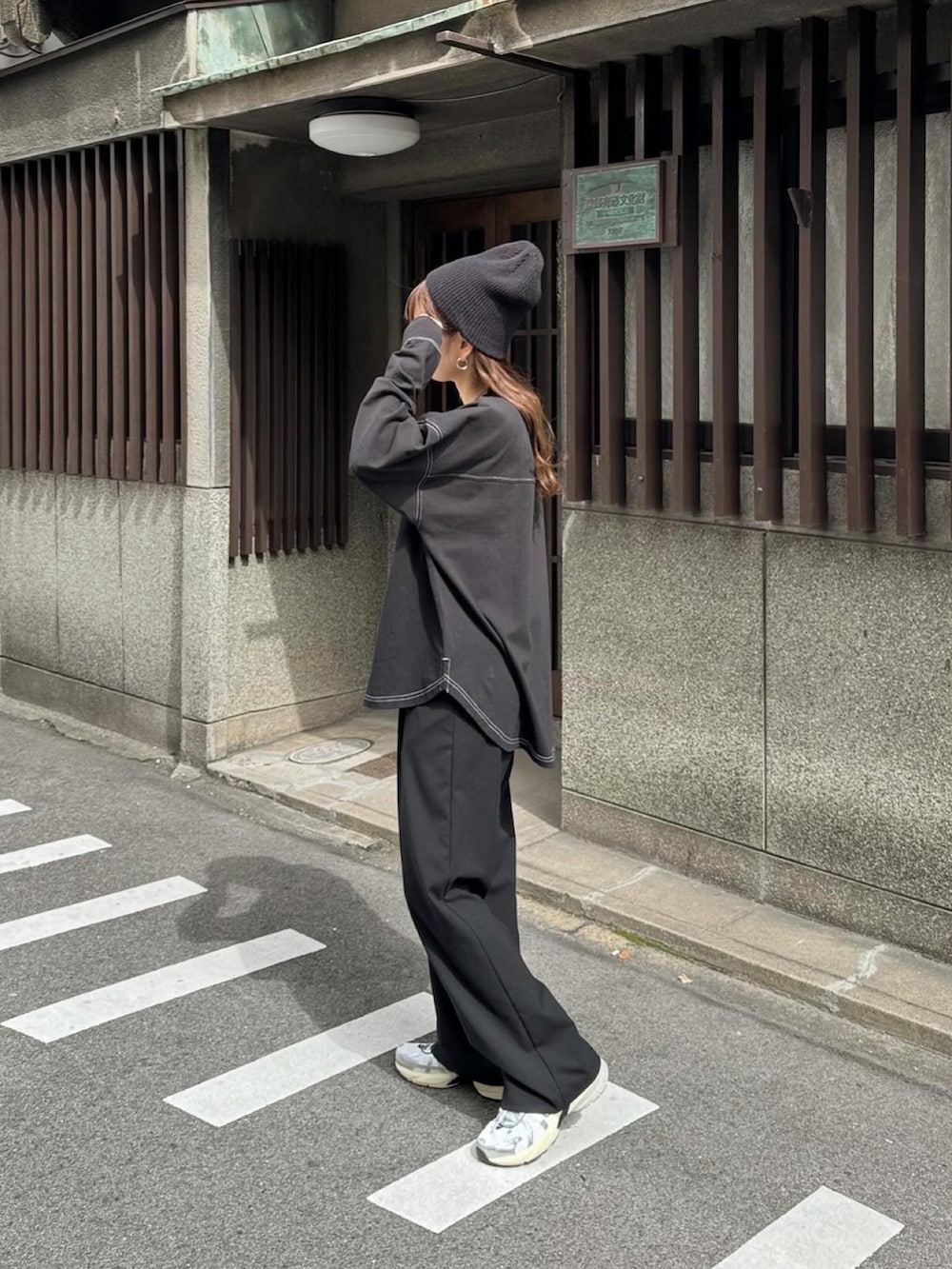 ブラック系のTシャツ/カットソー、ブラック系のスラックス、ホワイト系のスニーカーを着用したレディースの春コーディネートの4枚目の写真