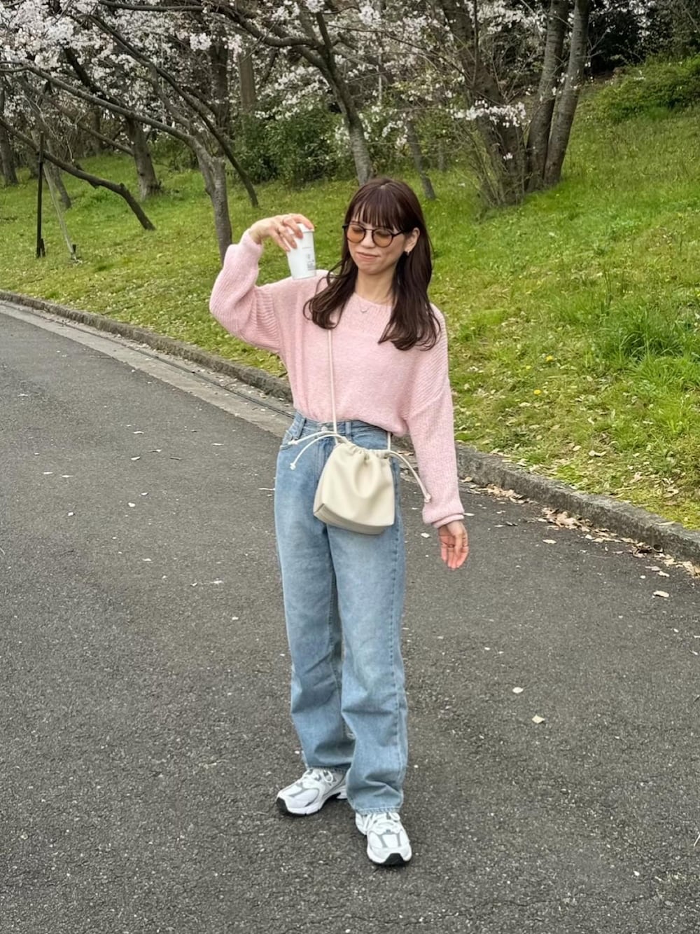 ブルー系のデニムパンツ、ピンク系のニット/セーター、ホワイト系のショルダーバッグを着用したレディースの春コーディネートの3枚目の写真