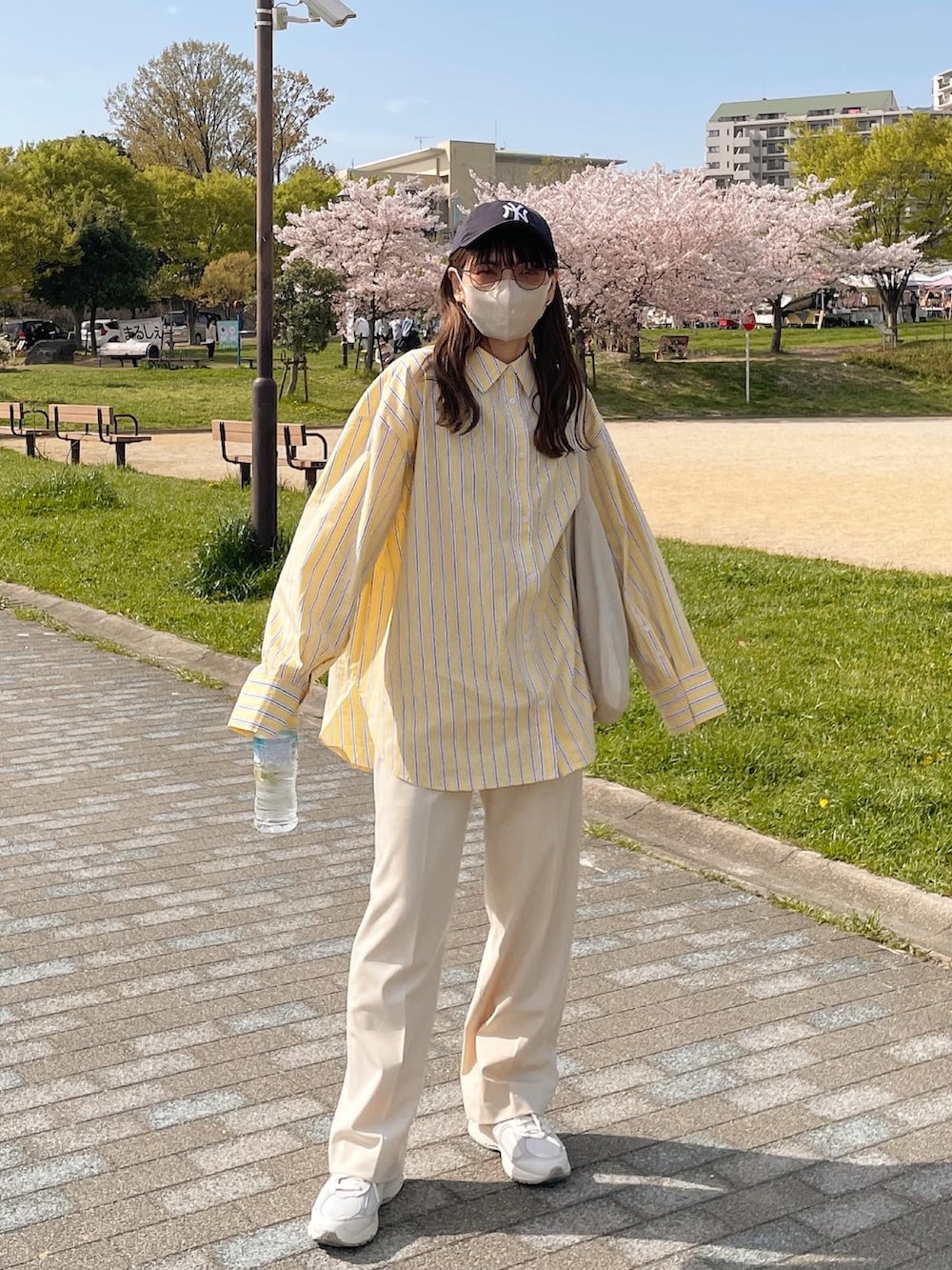 イエロー系のシャツ/ブラウス、ホワイト系のトートバッグ、ホワイト系のスニーカーを着用したレディースの春コーディネートの4枚目の写真