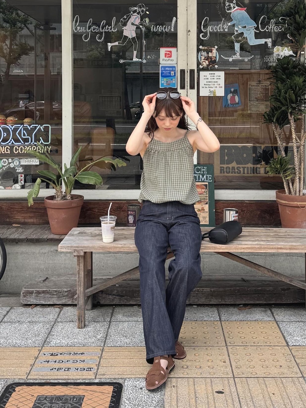 グリーン系のタンクトップ、ブルー系のデニムパンツ、ブラック系のショルダーバッグを着用したレディースの夏コーディネートの2枚目の写真