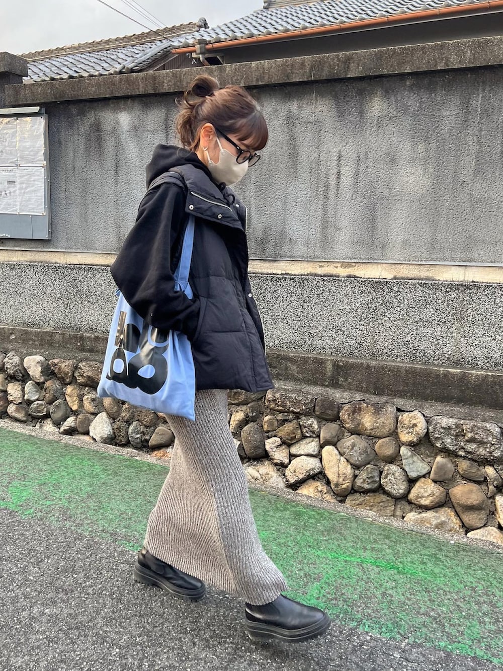 ブラック系のダウンベスト、グレー系のスカート、ブラック系のブーツを着用したレディースの冬コーディネートの4枚目の写真