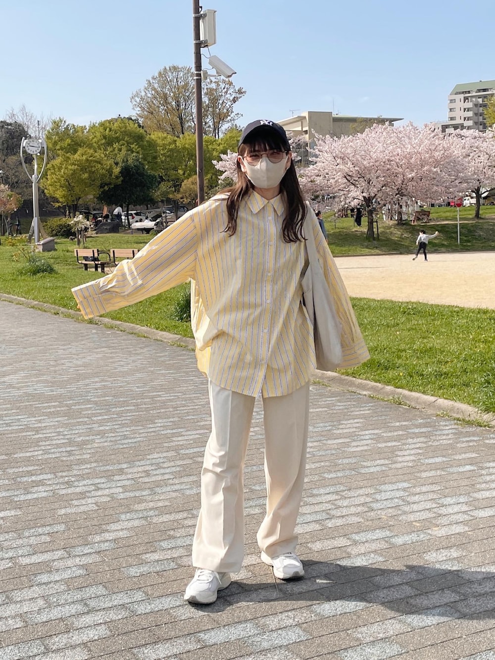 イエロー系のシャツ/ブラウス、ホワイト系のトートバッグ、ホワイト系のスニーカーを着用したレディースの春コーディネートの2枚目の写真