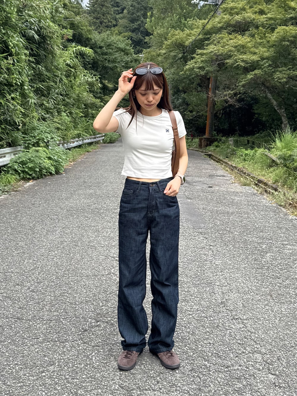 ブルー系のデニムパンツ、ブラウン系のスニーカーを着用したレディースの夏コーディネートの2枚目の写真