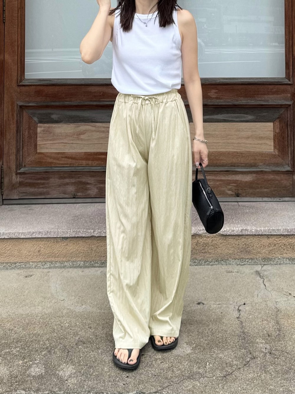 ホワイト系のタンクトップ、ベージュ系のその他パンツ、ブラック系のショルダーバッグを着用したレディースの夏コーディネートの3枚目の写真