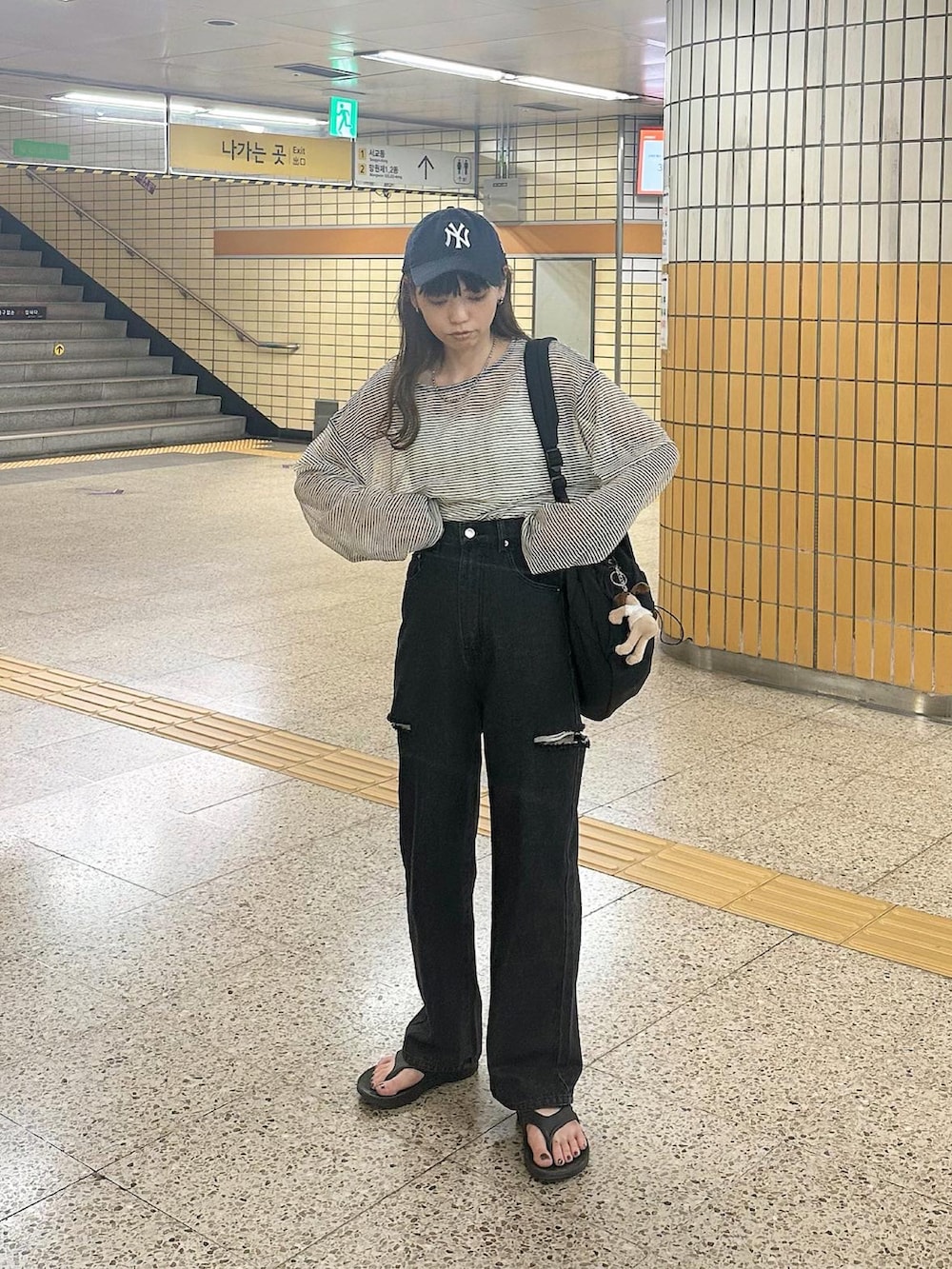 ブラック系のデニムパンツ、ホワイト系のTシャツ/カットソー、ブルー系のキャップを着用したレディースの春コーディネートの5枚目の写真