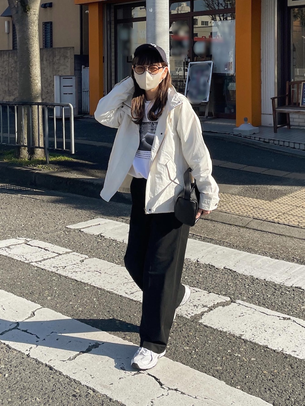 ホワイト系のマウンテンパーカー、ブルー系のキャップを着用したレディースの春コーディネートの4枚目の写真