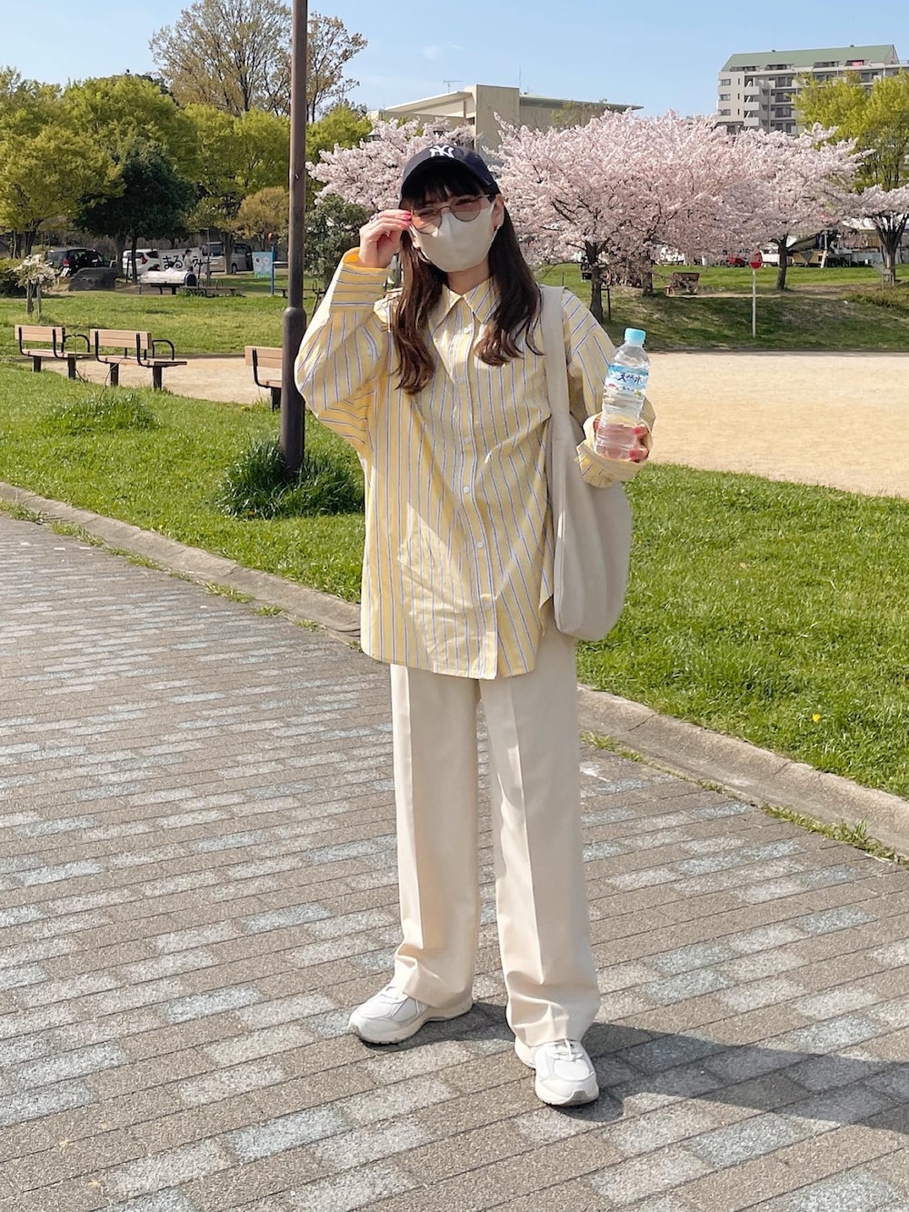 イエロー系のシャツ/ブラウス、ホワイト系のトートバッグ、ホワイト系のスニーカーを着用したレディースの春コーディネートの5枚目の写真