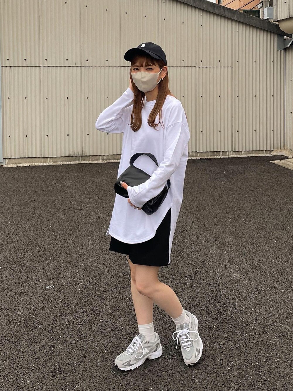 ホワイト系のTシャツ/カットソー、ベージュ系のスニーカー、ブラック系のキャップを着用したレディースの秋コーディネートの2枚目の写真