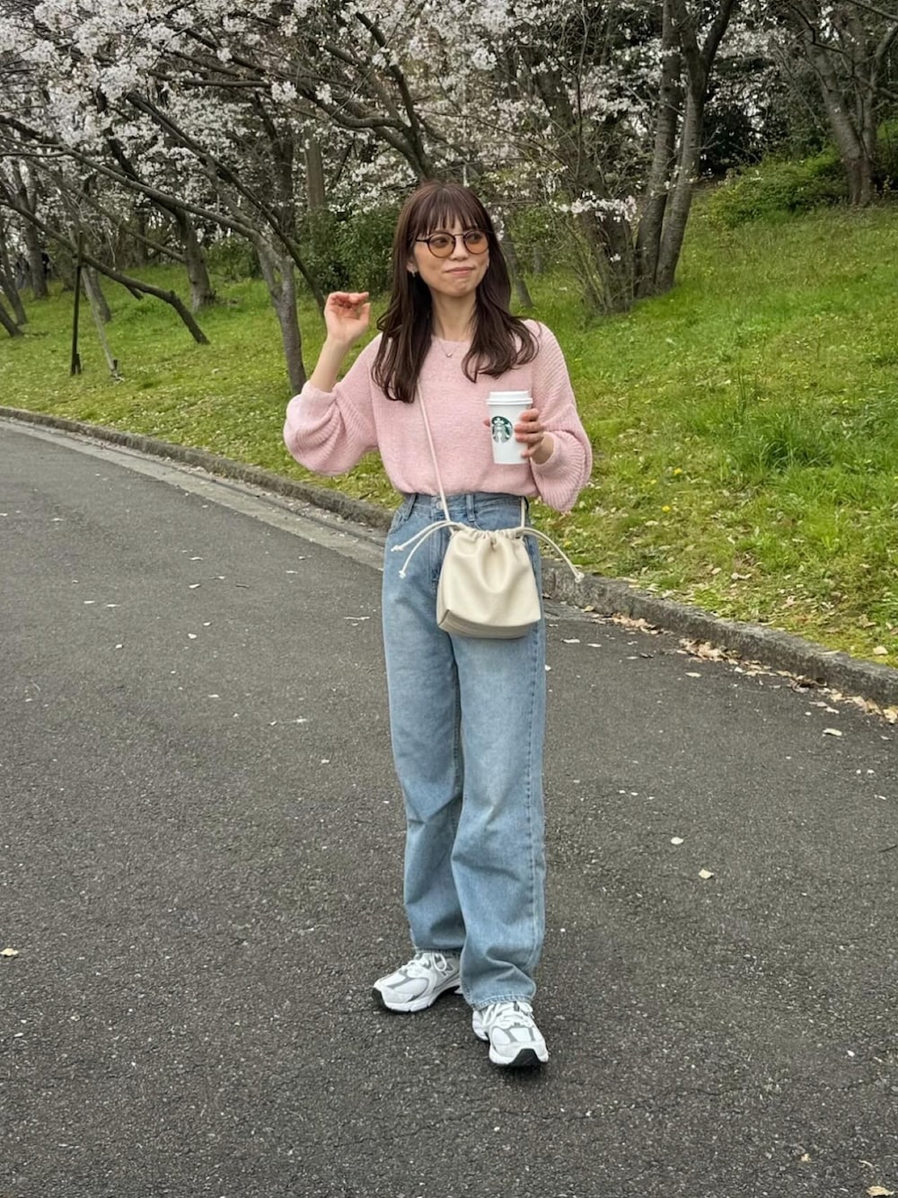 ブルー系のデニムパンツ、ピンク系のニット/セーター、ホワイト系のショルダーバッグを着用したレディースの春コーディネートの4枚目の写真