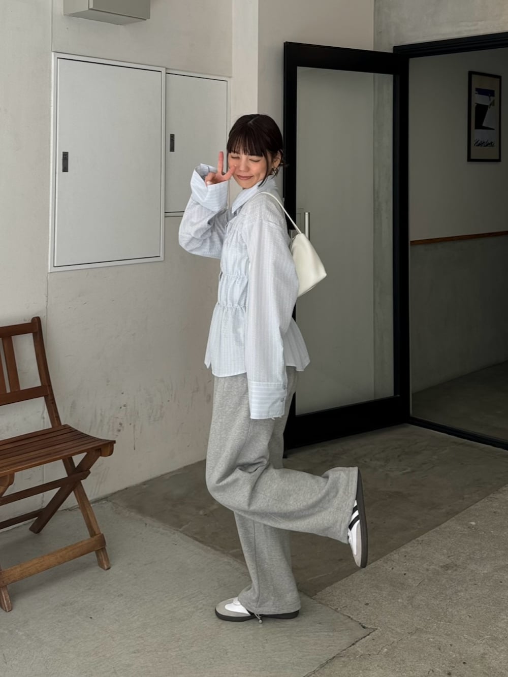 ブルー系のシャツ/ブラウス、グレー系のスウェットパンツ、ホワイト系のハンドバッグを着用したレディースの春コーディネートの3枚目の写真