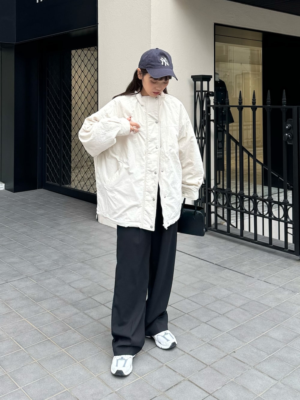 ホワイト系のブルゾン、ブラック系のスラックスを着用したレディースの秋コーディネートの2枚目の写真
