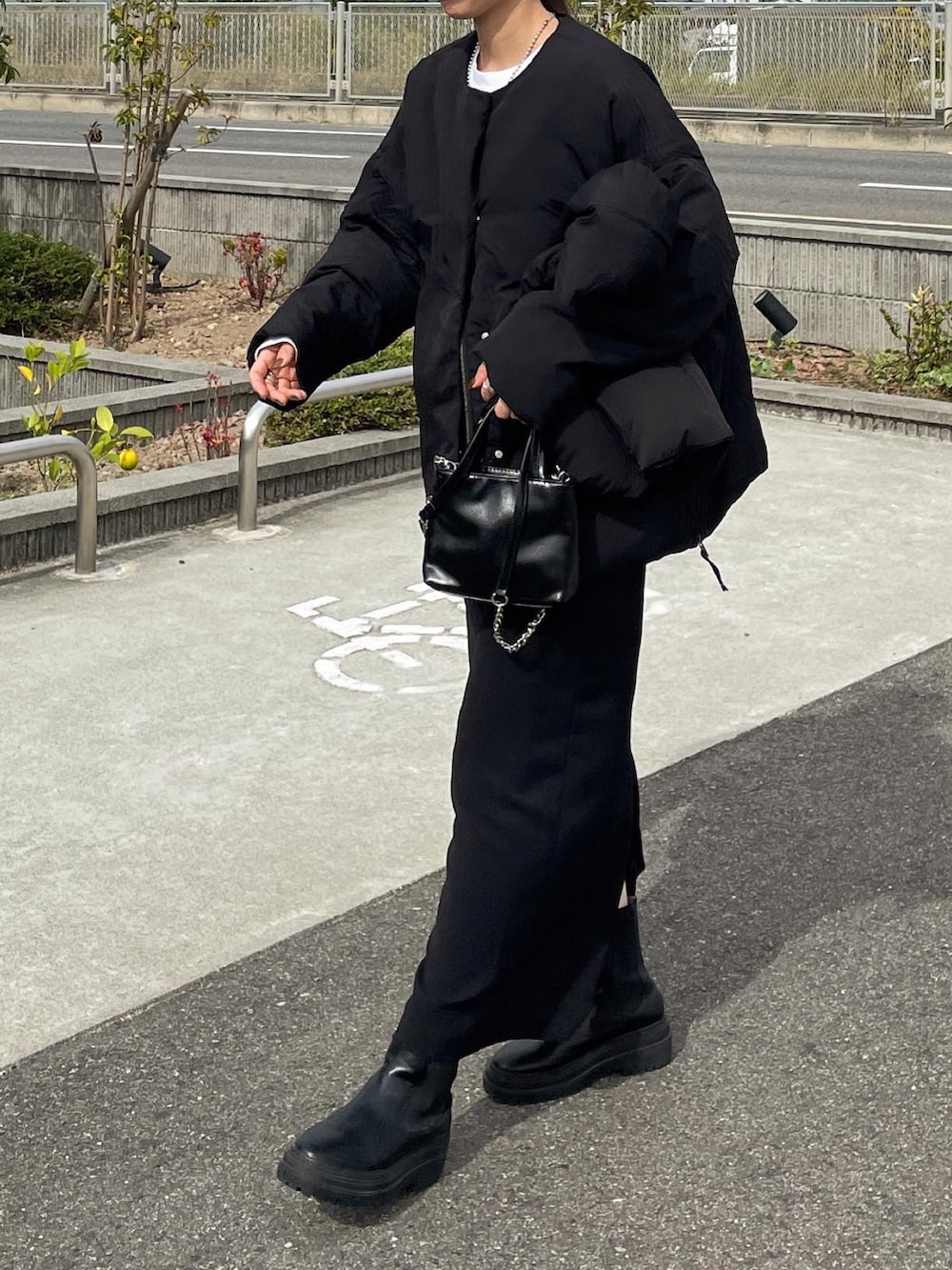 ブラック系のダウンジャケット/コート、ブラック系のスカート、ブラック系のショルダーバッグを着用したレディースの秋コーディネートの4枚目の写真