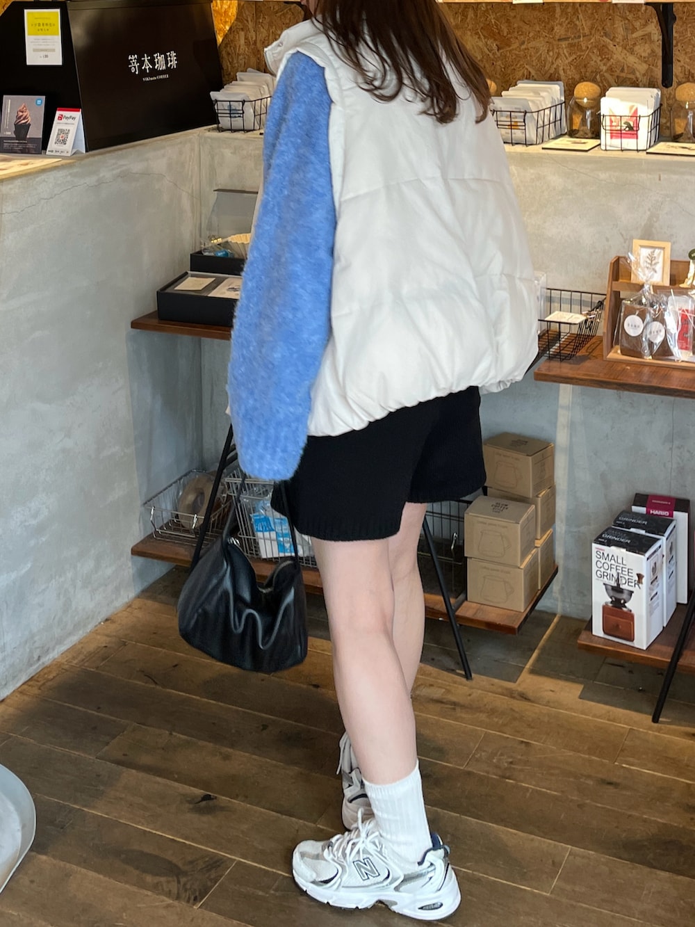 ブルー系のニット/セーター、ホワイト系のダウンベスト、ブラック系のその他パンツを着用したレディースの秋コーディネートの4枚目の写真