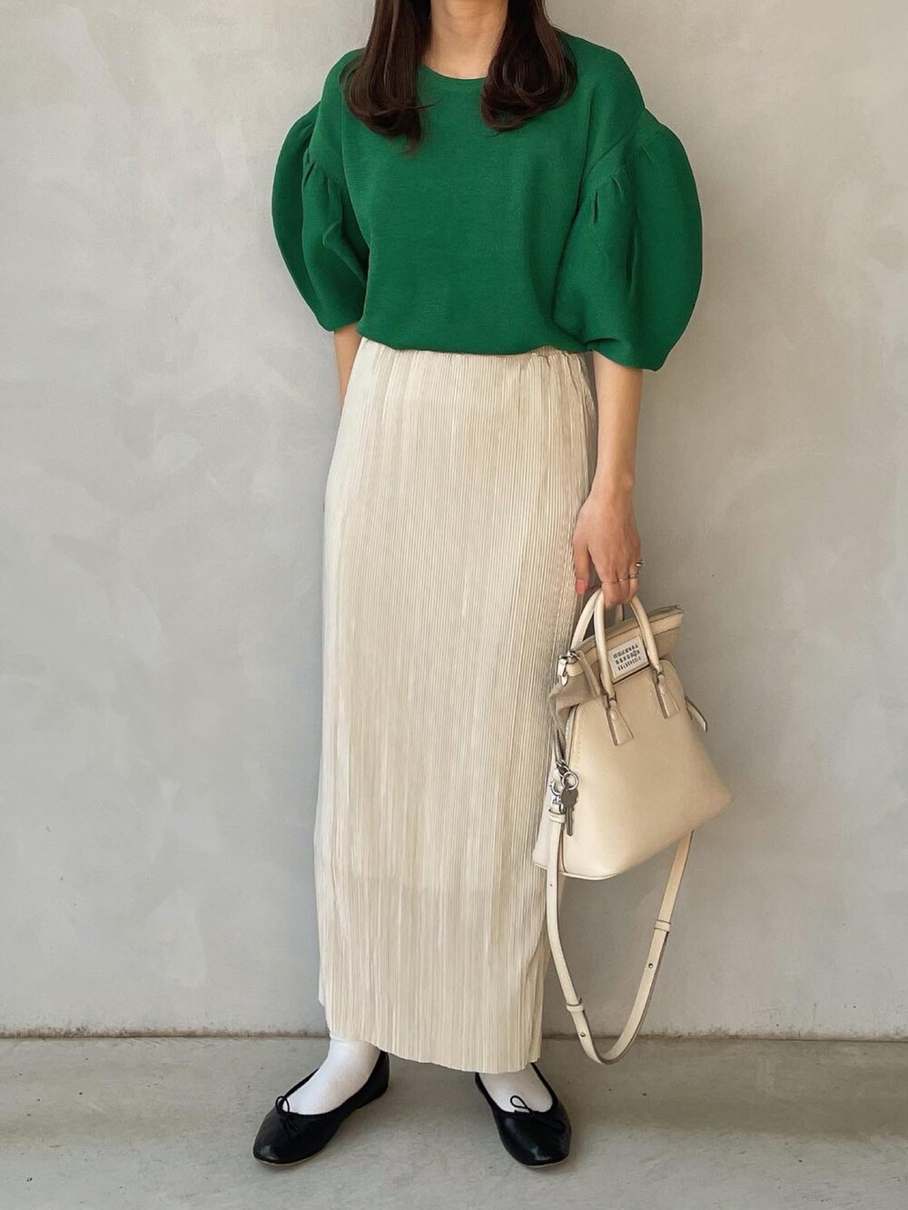 グリーン系のニット/セーター、ホワイト系のスカートを着用したレディースの春コーディネートの2枚目の写真