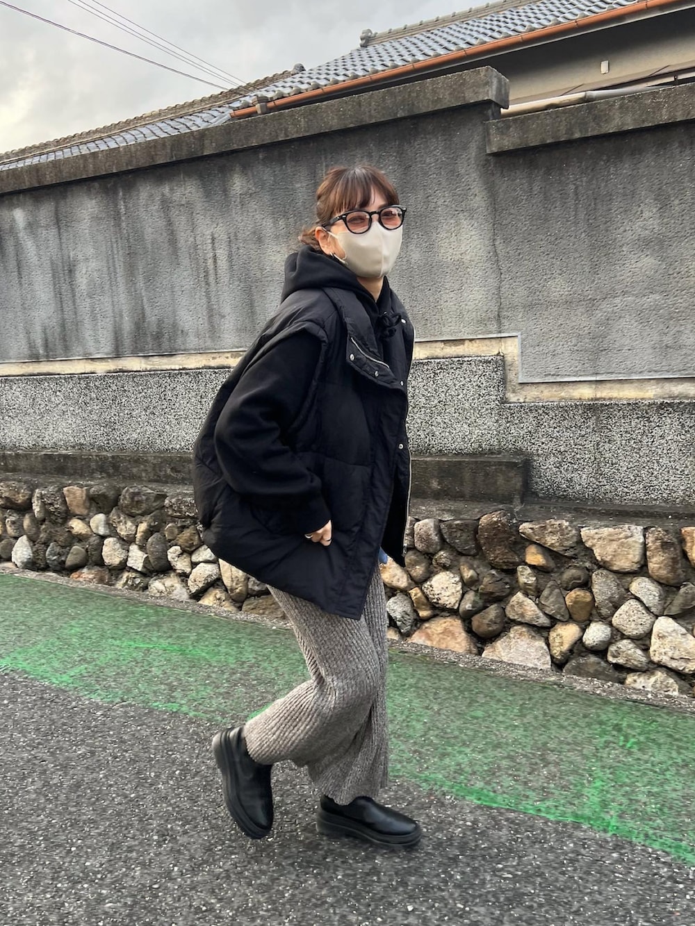 ブラック系のダウンベスト、グレー系のスカート、ブラック系のブーツを着用したレディースの冬コーディネートの5枚目の写真