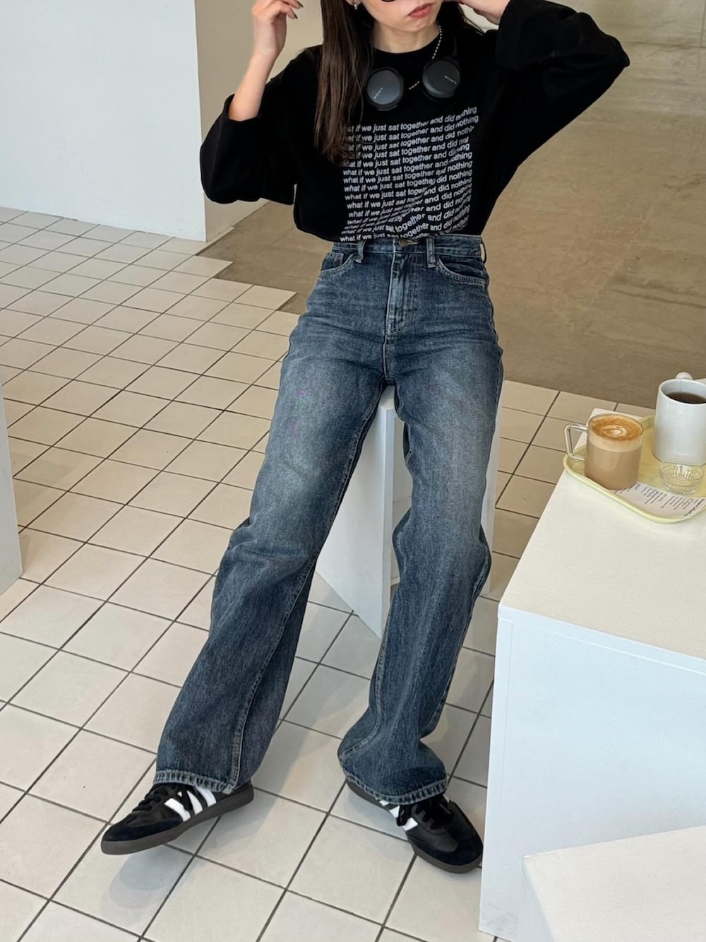 ブラック系のTシャツ/カットソー、ブルー系のデニムパンツ、ブラック系のスニーカーを着用したレディースの春コーディネートの2枚目の写真