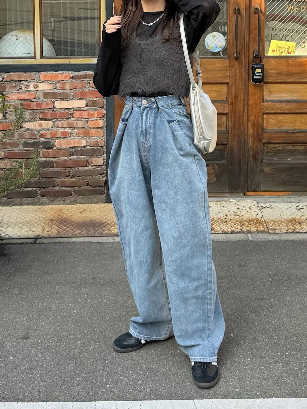 ブルー系のデニムパンツ、ホワイト系のショルダーバッグ、ブラック系のスニーカーを着用したレディースの冬コーディネートの3枚目の写真