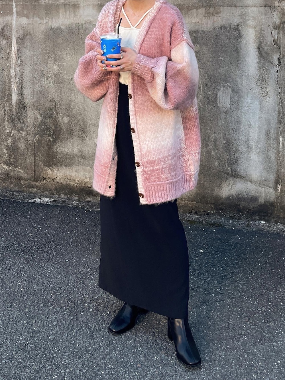 ピンク系のカーディガン/ボレロ、ブラック系のスカート、ホワイト系のキャミソールを着用したレディースの秋コーディネートの4枚目の写真
