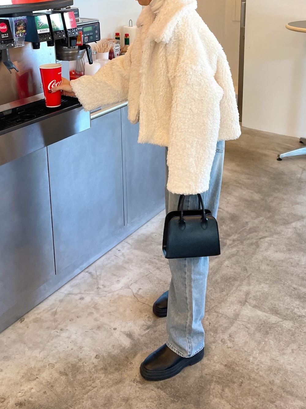 ホワイト系のその他アウター、ブルー系のデニムパンツ、ブラック系のショルダーバッグを着用したレディースの冬コーディネートの3枚目の写真