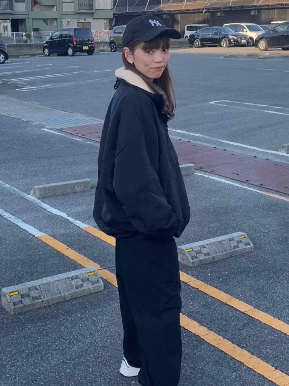 ブラック系のブルゾン、ブルー系のキャップを着用したレディースの秋コーディネートの2枚目の写真